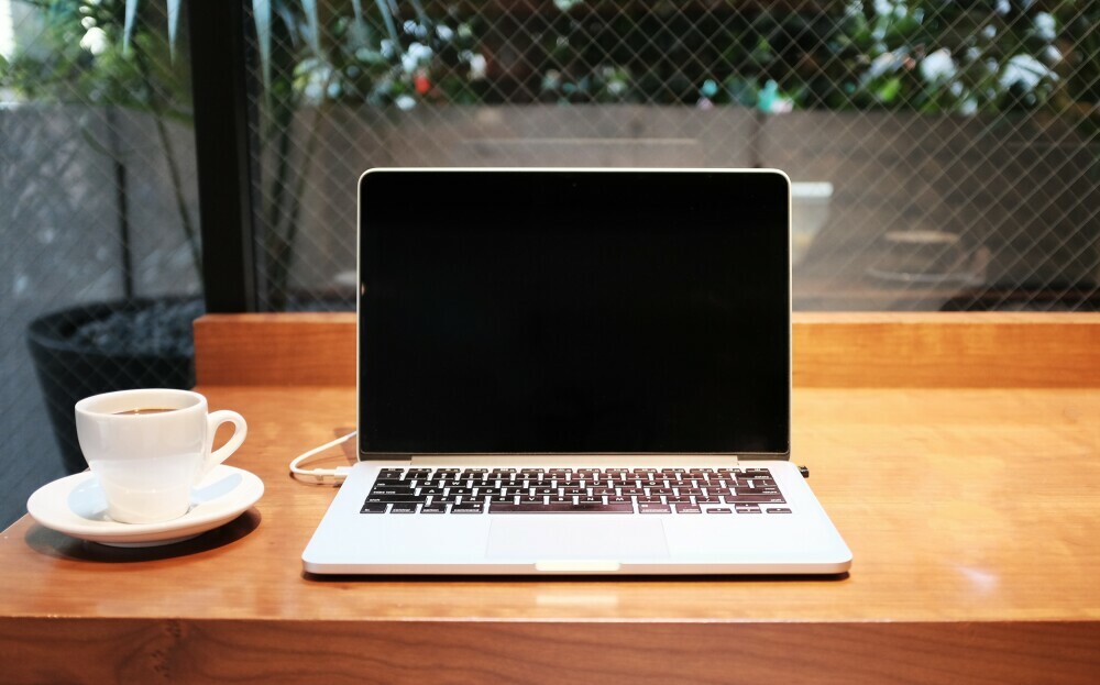 Laptop on wooden table with coffee cup